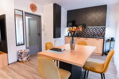 a kitchen and dining room with a wooden table and chairs at Bella Mura Golden Apartment in Moravske Toplice