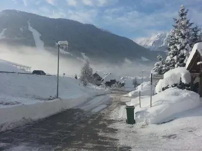 a snow covered road with a mountain in the background at Apartments Balon in Kranjska Gora