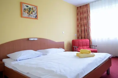 a bedroom with a bed and a red chair at Penzion Letališče in Murska Sobota