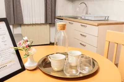a bottle on a tray with cups on a table at Guesthouse Špenko in Kamnik