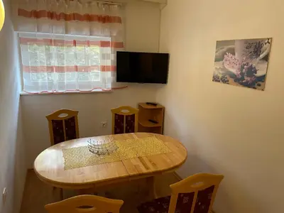 a dining room with a wooden table and a television at Martinov dom in Kranjska Gora