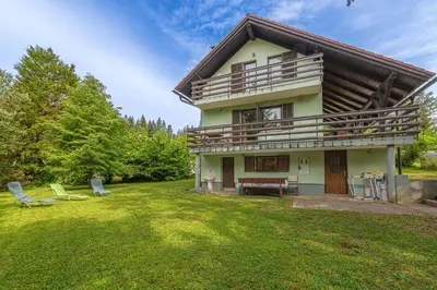 a house with a balcony and two chairs in the yard at House Fortin With Sauna Near Bloke Lake - Happy Rentals in Velike Bloke