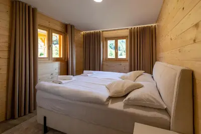 a bedroom with a large white bed with windows at Martinova izba - Family Bungalows in Laško
