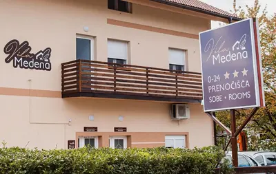 a sign in front of a building with a balcony at Rooms Vila Medena in Brežice