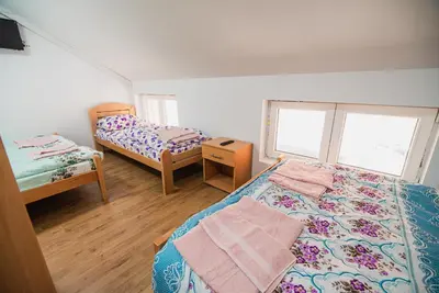 a bedroom with two beds and a table and two windows at Rooms Vila Medena in Brežice