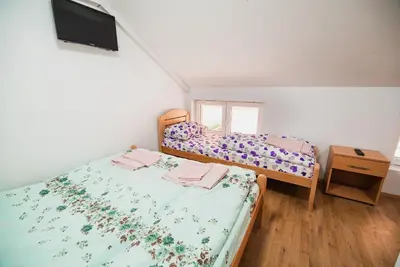 a bedroom with two beds and a tv on the wall at Rooms Vila Medena in Brežice