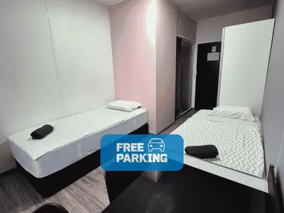 two beds in a room with a sign that says free parking at Hostel M in Maribor