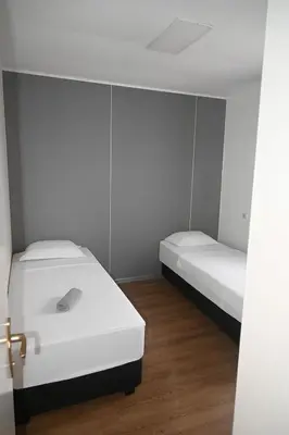 two beds in a room with white walls and wooden floors at Hostel M in Maribor