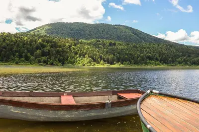 a boat on a lake with a mountain in the background at House Mavko Near Lake Cerknica - Happy Rentals in Grahovo