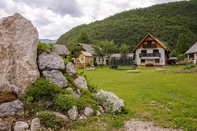 a house in a field with rocks in front of it at Chalet Pr Dobravc in Bohinj