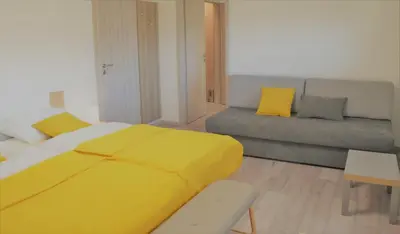 a bedroom with a yellow bed and a couch at Apartma Vila Zigmund in Cerknica