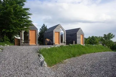 a house with orange doors and a gravel driveway at Hiška-Glamping in Ajdovščina
