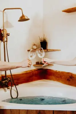 a person holding wine glasses in a bath tub at Treehouse Drevesna hiška Štrkovo gnezdo Ranč Jureš in Ljutomer
