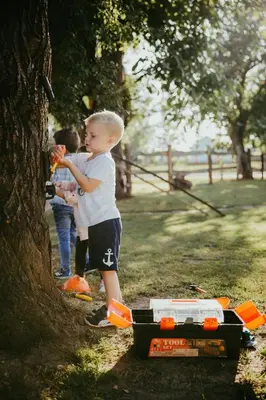 a young boy standing next to a tree eating food at Treehouse Drevesna hiška Štrkovo gnezdo Ranč Jureš in Ljutomer