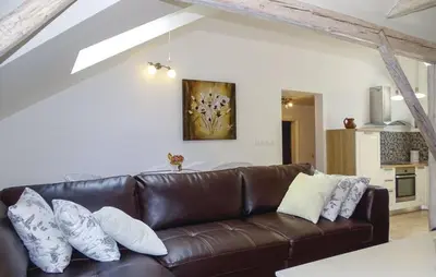 a living room with a brown leather couch with pillows at Apartmaji Čujež in Rečica ob Savinji