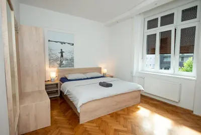 a bedroom with a bed and two windows at Viva Rooms in Ljubljana