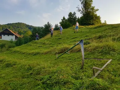 a group of people walking on a grassy hill at Notranjska hiša - traditional country house, close to the world attraction Cerknica lake in Begunje pri Cerknici