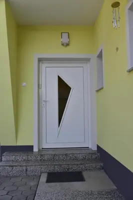 a white door with a triangle on a yellow wall at Primula Apartment in Blejska Dobrava