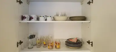 a shelf with glasses and plates on it at Primula Apartment in Blejska Dobrava