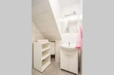 a white bathroom with a sink and a mirror at Apartma N'Poznam Tobačna in Ljubljana