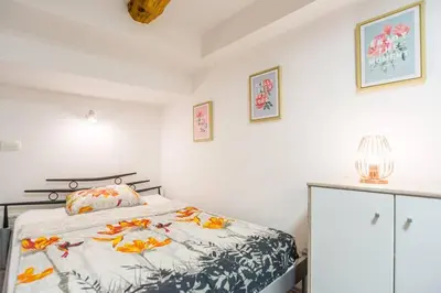 a white bedroom with a bed with leaves on it at Apartma N'Poznam Tobačna in Ljubljana