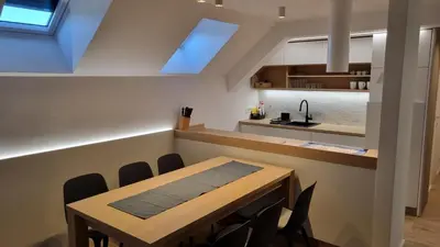 a dining room with a table and a kitchen at BledLake4U Apartment in Bled