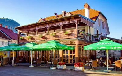 a restaurant with green umbrellas in front of a building at Guest House Pri Cesarju in Kamnik