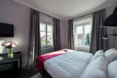 a bedroom with a bed and two windows at Kollmann Rooms and Apartments in Ljubljana