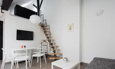a living room with a spiral staircase and a table and chairs at Kollmann Rooms and Apartments in Ljubljana