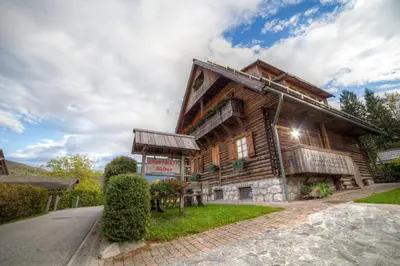a log house with a road in front of it at Apartments Brina in Bohinj