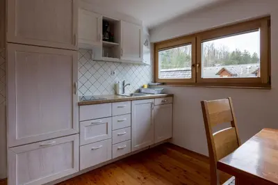 a kitchen with white cabinets and a window and a table at Apartments Brina in Bohinj