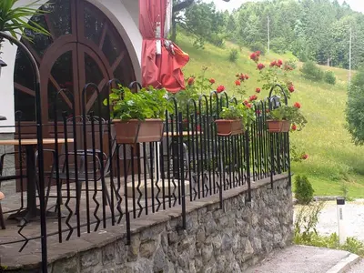 a fence with potted plants on a stone wall at B&B Na Kluk in Idrija