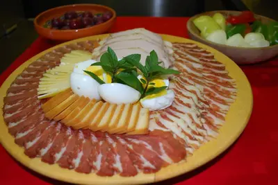 a plate of meats and cheese on a red table at Farm Stay Rotovnik - Plesnik in Slovenj Gradec