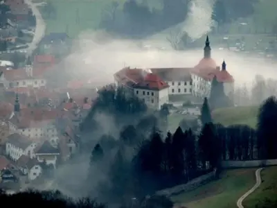 a large building on top of a hill in the clouds at Rooms and Apartment Na poljani in Škofja Loka