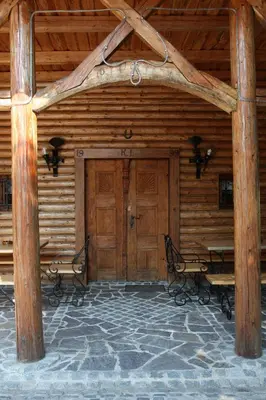 a wooden cabin with two benches and a wooden door at Guesthouse Pri Zalogarju in Železniki