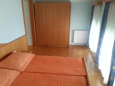 a bedroom with a bed and a wooden cabinet at Penzion Zeleni Kakadu in Maribor