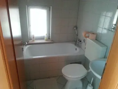 a bathroom with a tub and a toilet and a window at Penzion Zeleni Kakadu in Maribor