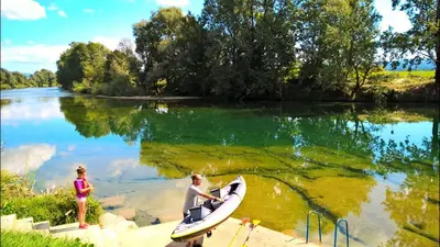 a man sitting on a surfboard next to a river at Holiday resort Bela krajina - Glamping and Mobile Homes in Metlika