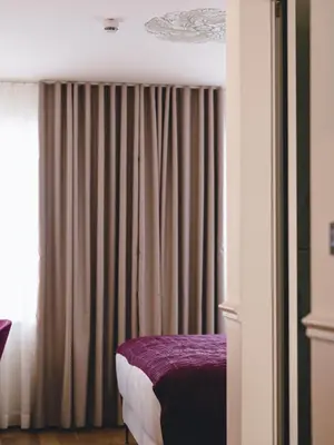 a bedroom with a bed and a window with curtains at Hotel Heritage in Ljubljana