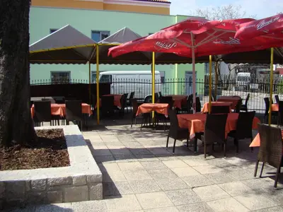 a group of tables and chairs with red umbrellas at Gostilna pri Dragici, gostilna s prenočišči, d.o.o. in Sežana