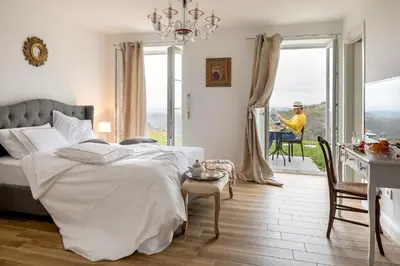 a bedroom with a bed and a table and a man sitting in a chair at Peterc Vineyard Estate in Kojsko