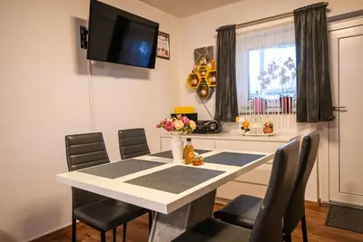 a dining room with a white table and chairs at Honey Apartment Lendava in Lendava