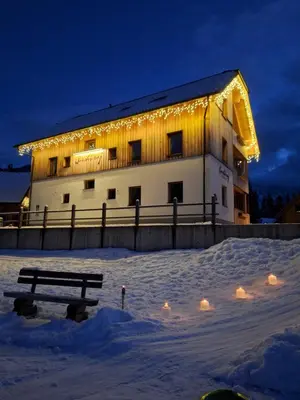 a building with lights on it in the snow at Apartments Gorski raj in Kranjska Gora