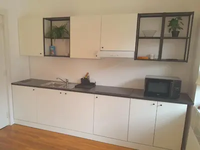 a kitchen with white cabinets and a microwave at Rooms Miklošičeva in Ljubljana