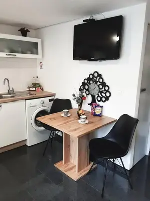 a kitchen with a wooden table with chairs and a sink at R.I.Š.-Rest in Šiška Duplex in Ljubljana