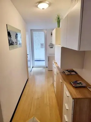 a kitchen with white cabinets and a wooden floor at R.I.Š.-Rest in Šiška Duplex in Ljubljana