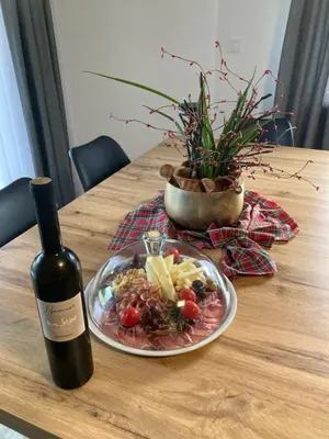 a table with a plate of food and a bottle of wine at Apartment Lida in Podčetrtek