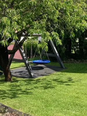 a swing set under a tree in a park at Apartment Lida in Podčetrtek