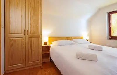 a bedroom with two beds with white sheets and a window at Old Farm House Breg in Žirovnica