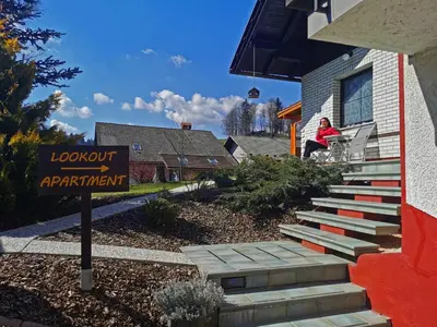 a woman sitting on the front porch of a house at Lookout Resort in the green heart of Slovenia in Rovte